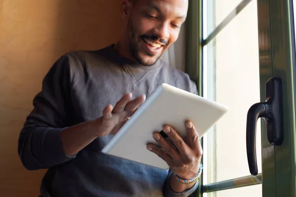 Lächelnder afrikanischer Schwarzer mit Tablet im heimischen Wohnzimmer. — Stockfoto