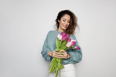 Gri arka plan üzerinde izole renkli Lale buketi tutan yakışıklı bir genç kadın portresi