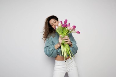 Gri arka plan üzerinde izole renkli Lale buketi tutan neşeli bir genç kadın portresi. Kopya hamur alanı