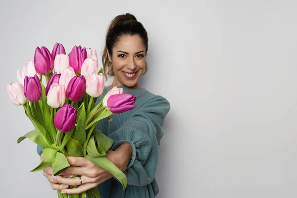 Portrait of a cheerful young woman holding colored tulips bouquet isolated over gray background. Copy paste space — Stock Photo, Image