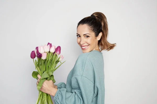 Beautiful girl with big bouquet flowers tulips in hands on a light background — Stock Photo, Image