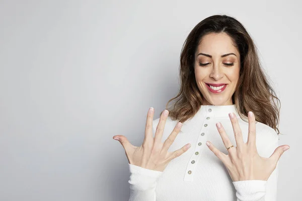 Handsome positive woman in white shirt looking at camera and showing hands gesture while standing isolated on gray background. — Stock Photo, Image