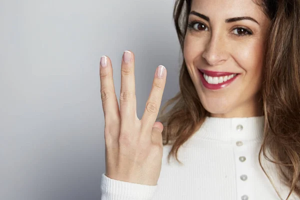 Handsome positive woman in white shirt looking at camera and showing hands gesture while standing isolated on gray background. — Stock Photo, Image