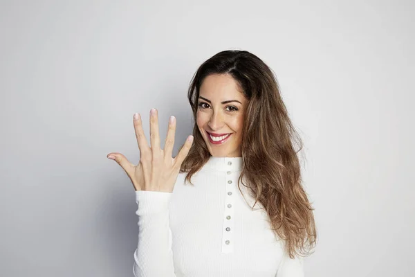 Handsome positive woman in white shirt looking at camera and showing hands gesture while standing isolated on gray background. — Stock Photo, Image