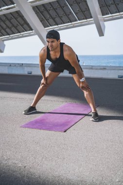 Kaslı erkek atlet sprinter germe egzersiz, açık havada egzersiz, dışarıda koşu yapıyor. sağlıklı yaşam tarzı.