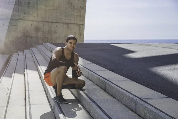 Musculoso atleta masculino sprinter descansando después de ejercicios al aire libre en forma de cruz. Estilo de vida saludable . —  Fotos de Stock