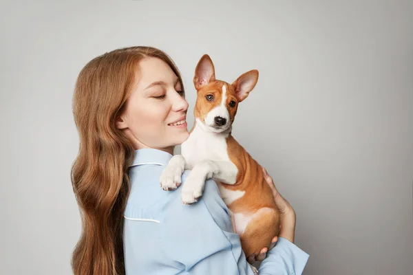 白い背景の赤い髪の美少女受け入れ子犬。低温犬と白の魅力的な女性のスタジオ ポートレート — ストック写真