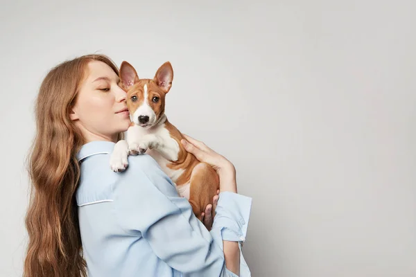 Jolie jeune femme embrassant et embrassant son chien basenji chiot. Amour entre chien et propriétaire. Isolé sur fond blanc — Photo