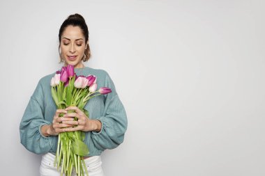 Gri arka plan üzerinde izole renkli Lale buketi tutan bir İspanyol genç kadın portresi. Kopya hamur alanı
