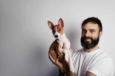 Beyaz bir arka plan karşı şirin alçaklık köpek yavrusu köpek vasıl ev ile mutlu sakallı adam.
