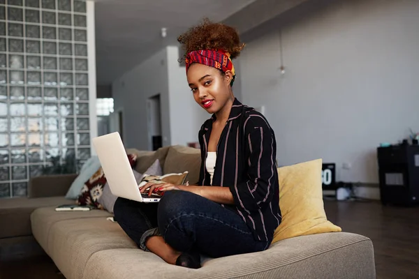 Confident american african female blogger working remotely on digital netbook with internet text. African woman copywriter typing article for website on keyboard of modern laptop computer at home