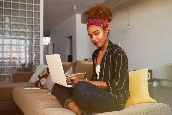 Bonita blogueira africana americana trabalhando remotamente em netbook digital com texto na internet. Mulher africana copywriter artigo de digitação para o site no teclado do computador portátil moderno em casa — Fotografia de Stock