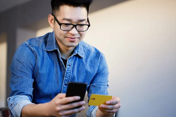 Fiatal ázsiai férfi kezében hitelkártyával és mobiltelefonnal. Technológia, Internet Banking, e-kereskedelem és online vásárlás. — Stock Fotó