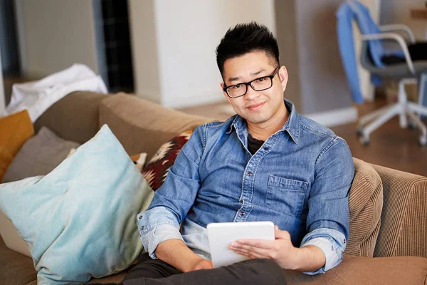 Jeune homme asiatique utilisant sa tablette électronique tout en se relaxant sur le canapé confort au studio de coworking — Photo