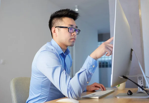 Jovem asiático blockchain profissional vestindo camisa e óculos de trabalho enquanto sentado na frente do computador desktop em co-working escritório . — Fotografia de Stock