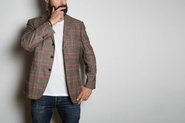 Kendinden emin sakallı işadamı modeli, beyaz arka planda rahat ceket ve boş beyaz t-shirt prim yaz pamuk pozlar. Mockup kopya yapıştırma alanı