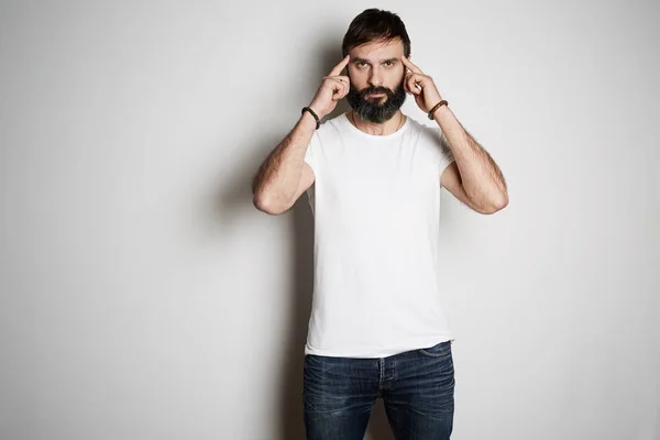 Young brutal tattooed bearded guy poses in blue jeans and blank white t-shirt premium summer cotton, on white background. — Stock Photo, Image