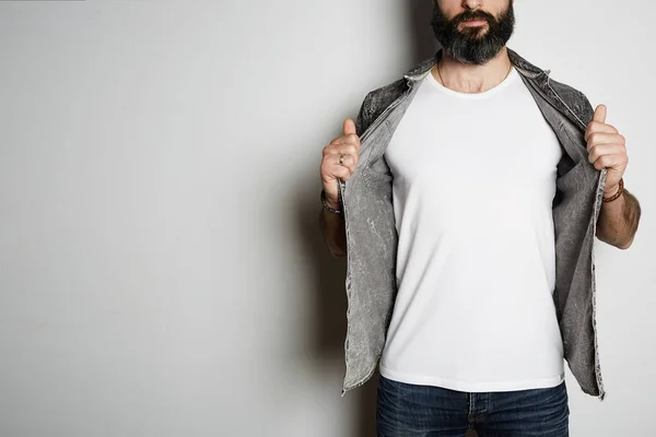 Handsome brutal bearded hipster model poses in black jeans shirt and blank white t-shirt premium summer cotton, on white background. Copy paste Advertisement. — Stock Photo, Image