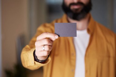 Sakallı iş adamı, bulanık arka planda el ele boş siyah kartvizit tutuyor. Mockup Kopyala Yapıştır Boş Reklam.
