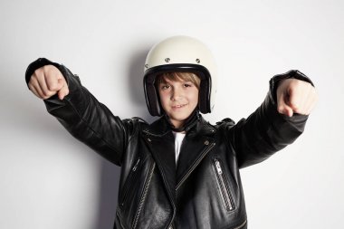 Siyah deri ceket ve beyaz moto kask genç yakışıklı neşeli genç çocuk Portresi beyaz arka plan üzerinde bir motosiklet binmek gibi davranarak.