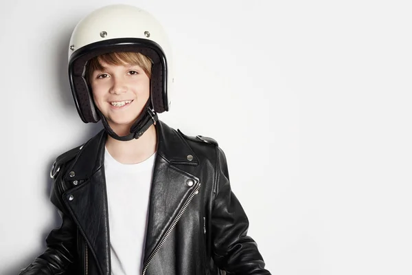 Joven feliz niño adolescente alegre en chaqueta de cuero negro y casco moto blanco sonriendo sobre fondo blanco . — Foto de Stock