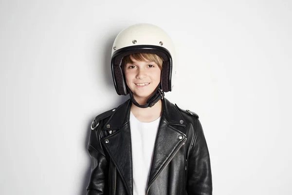 Retrato de Joven feliz hermoso niño adolescente en chaqueta de cuero negro y casco de moto blanco sonriendo sobre fondo blanco . — Foto de Stock