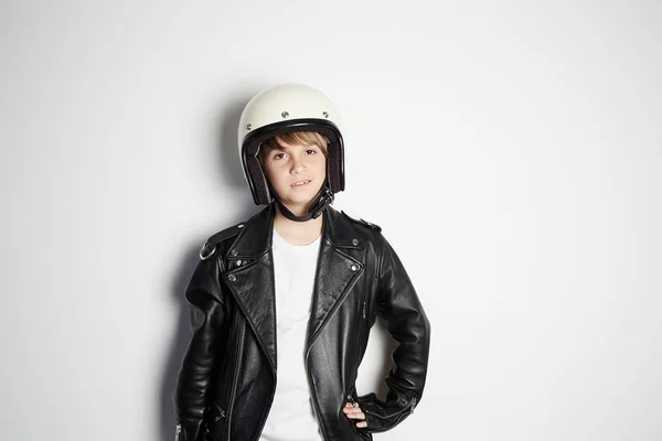 Retrato de joven fresco hermoso adolescente niño en chaqueta de cuero negro y casco de moto blanco sonriendo sobre fondo blanco . — Foto de Stock