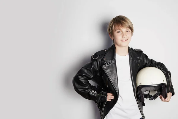 Портрет молодого крутого красивого подростка в черной кожаной куртке и держась за руку белый мотошлем улыбаясь на белом фоне . — стоковое фото