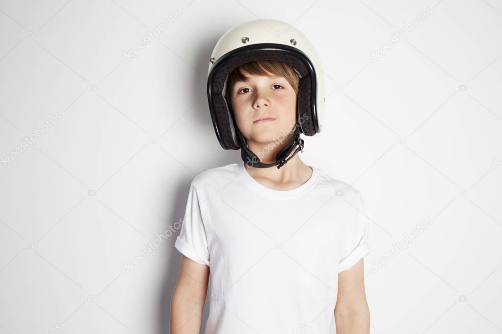 Portrait of young handsome cheerful teen in white tshirt preparing to ride a motorcycle isolated on white background.