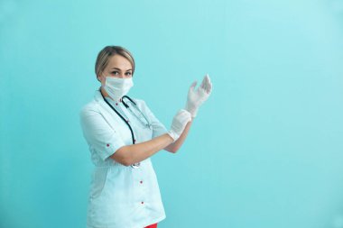 Kadın doktor veya hemşire bir maske, cüppe ve cerrahi eldiven mavi zemin üzerine koyarak stetoskop.