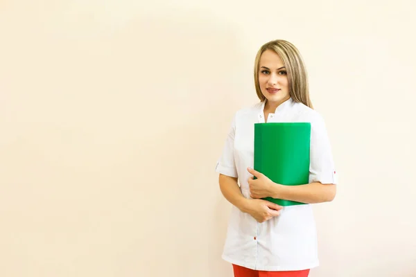 Улыбающаяся женщина-врач с зеленой папкой в форме стоя — стоковое фото