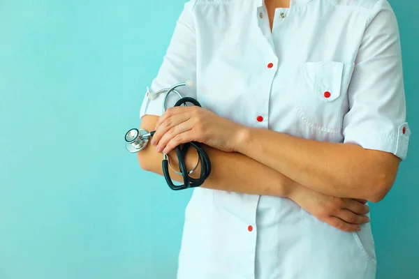 Женские руки доктора держат стетоскоп на светло-голубом фоне — стоковое фото