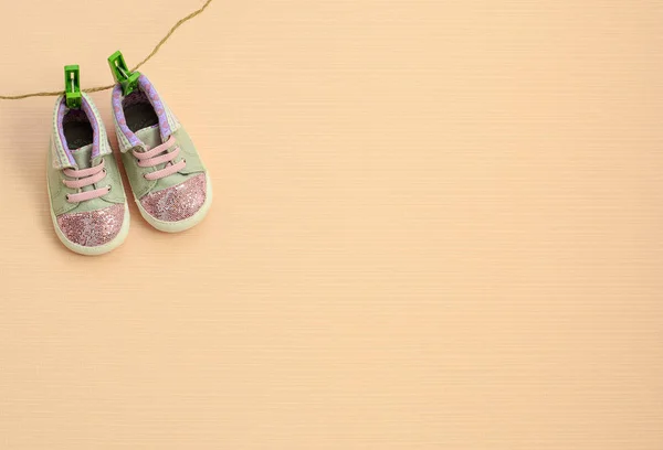 Buty sportowe dla dzieci wiszące na sznurki na jasnym tle — Zdjęcie stockowe