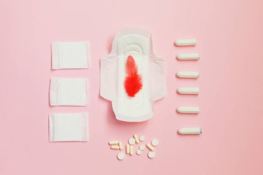 Kırmızı tüy ve hijyenik pedler ve emici levhalar üzerinde pembe bir arka plan
