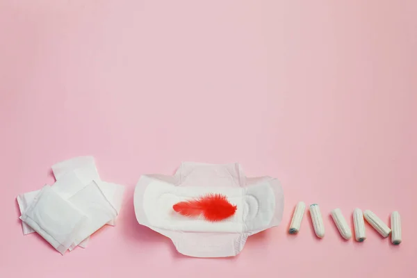Bulu merah dan pembalut sanitasi dan lembar penyerap pada latar belakang merah muda — Stok Foto
