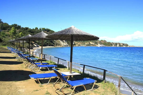 Рядки соломи парасольки і loungeron піщаного пляжу. Греція — стокове фото