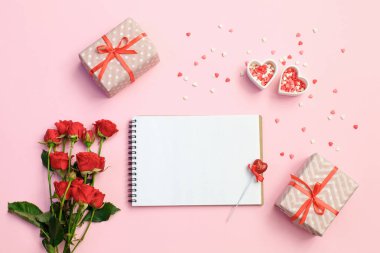 Hediye kutusu, çiçek ve kalpleri pembe bir arka plan üzerine açık boş defter. Sevgiliye arka plan.