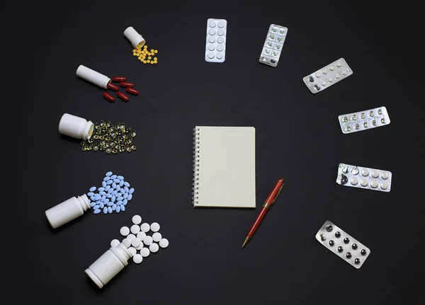 Различные таблетки с ноутбуком и карандашом на черном фоне — стоковое фото