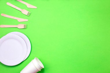 Bambu ahşap ve kağıt yeşil bir arka plan üzerinde yapılan çevre dostu tek kullanımlık mutfak eşyaları.