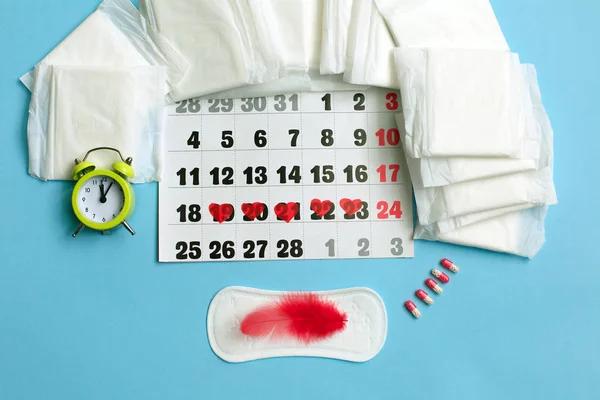 Konsep siklus menstruasi. Kalender menstruasi dengan pembalut, pil kontrasepsi, bunga dan jam weker . — Stok Foto