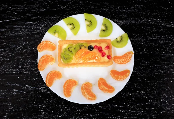 Healthy dessert with sweet cakes and fruits on a black table
