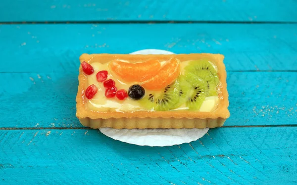 Sweet cakes with fruits on blue wooden table