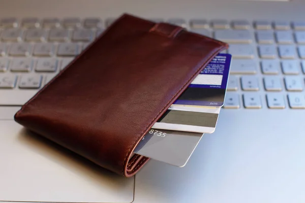 Credit cards in the wallet on the laptop keyboard.