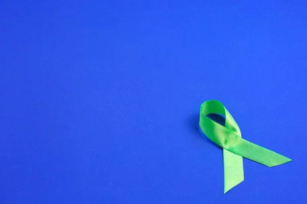 Licht groen lint op blauwe achtergrond. Leverkanker lymfoom bewustzijn. Gezondheidszorg en geneeskunde concept. — Stockfoto