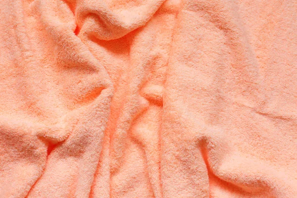 Soft peach fabric with waves and folds. Soft pastel textile texture.