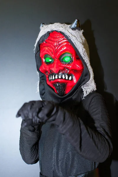 Mystery man holding red mask with bright green eyes. Anonymous social masking concept.