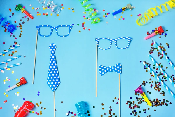 Urlaub oder Party Hintergrund mit Strohhalmen, Trillerpfeifen, Konfetti, lustigen Gläsern und Luftschlangen auf blauem Hintergrund. flache Verlegestile. — Stockfoto