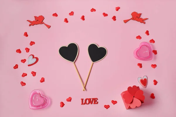 Den svatého Valentýna. Rám vyrobený z dárků, konfety srdce, andělé na růžovém pozadí. Valentinky den pozadí. — Stock fotografie