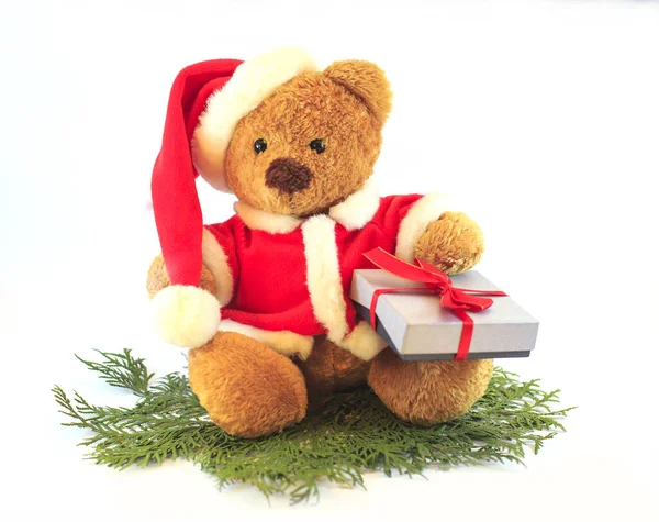 Speelgoed teddy bear dragen KERSTMUTS op witte achtergrond met gave in handen Stockfoto