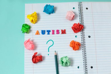 Renk ahşap harfler otizm renkli Word'den defter sayfası ve soru işareti ile çevrili bir kalem renkli kağıt buruşuk. Kavram görüntü